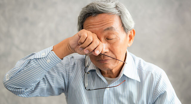 man rubbing eye holding glasses.jpg